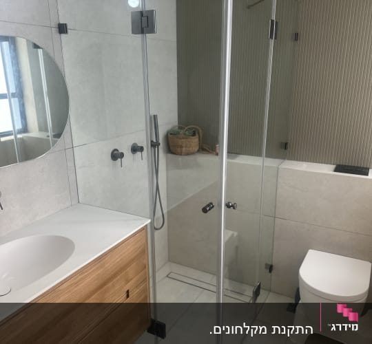חדר אמבטיה עם מקלחון זכוכית ושירותים